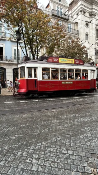 Elétrico vermelho circulando pelo centro de Lisboa