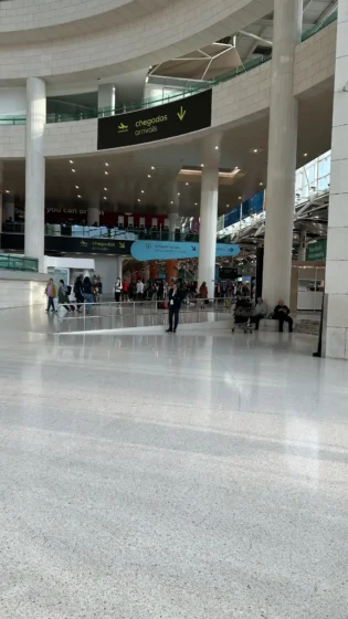 Área de chegadas do Aeroporto de Lisboa com sinalização para informações e táxis