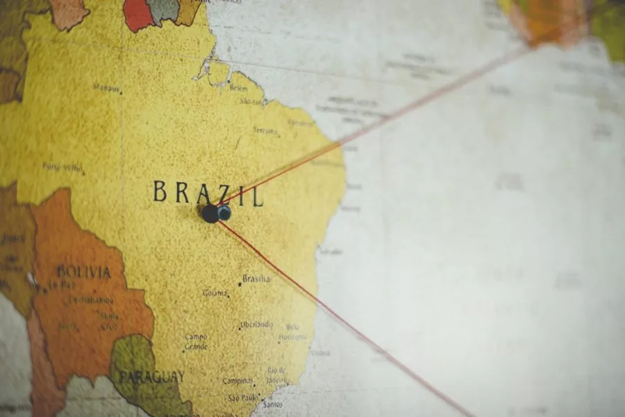 Foto de um mapa de parede com um pino em cima do Brasil