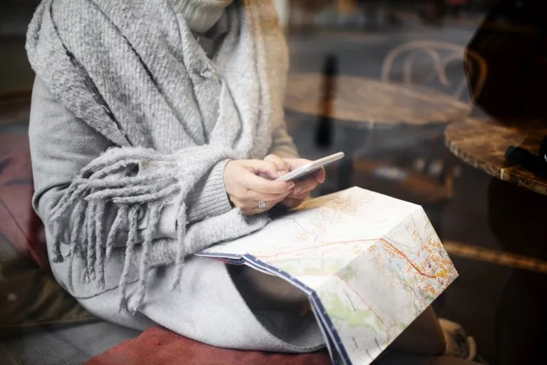 Idosa viajando sozinha mas com seu smartphone e seu mapa de viagem