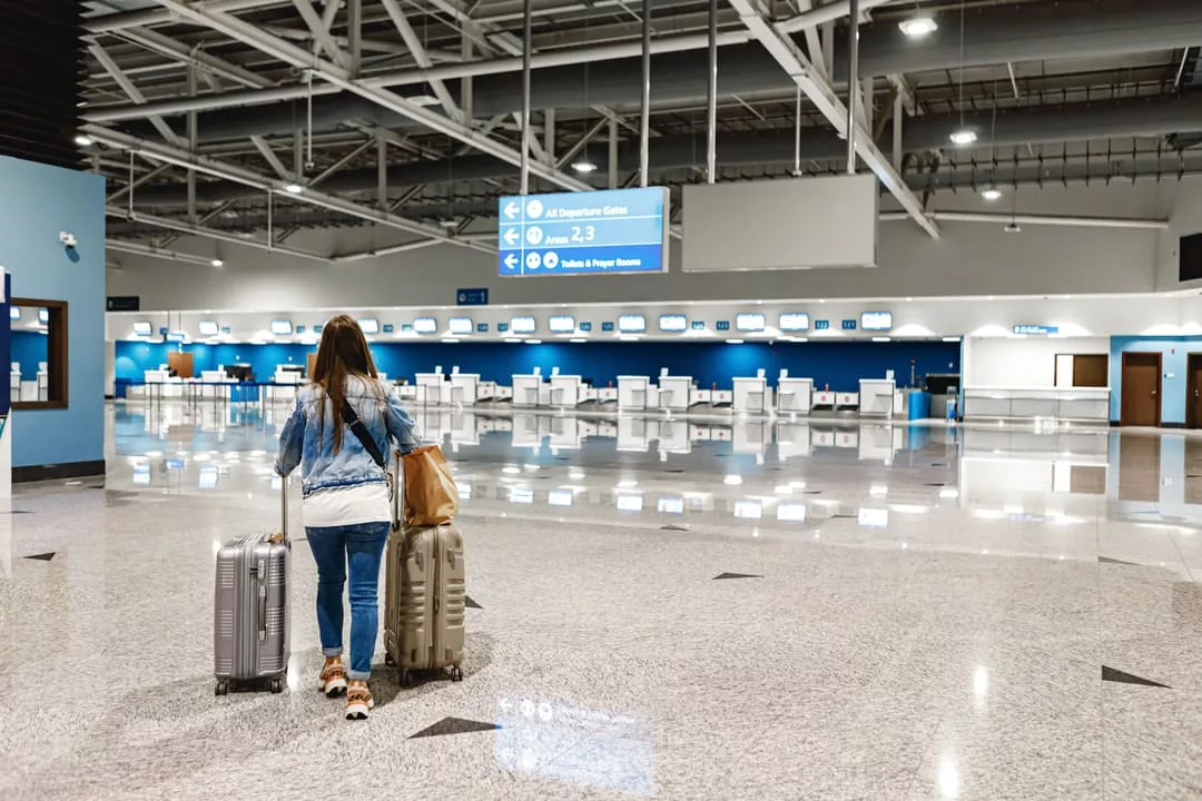 Jovem embarcando salão do aeroporto com duas malas